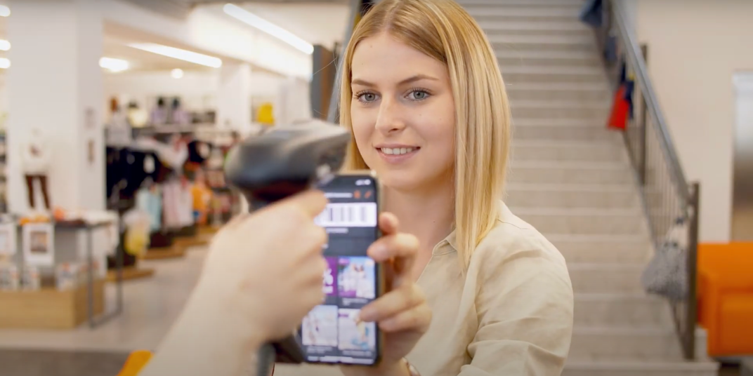 Woman showing barcode for customer benefit in a shopping store while paying