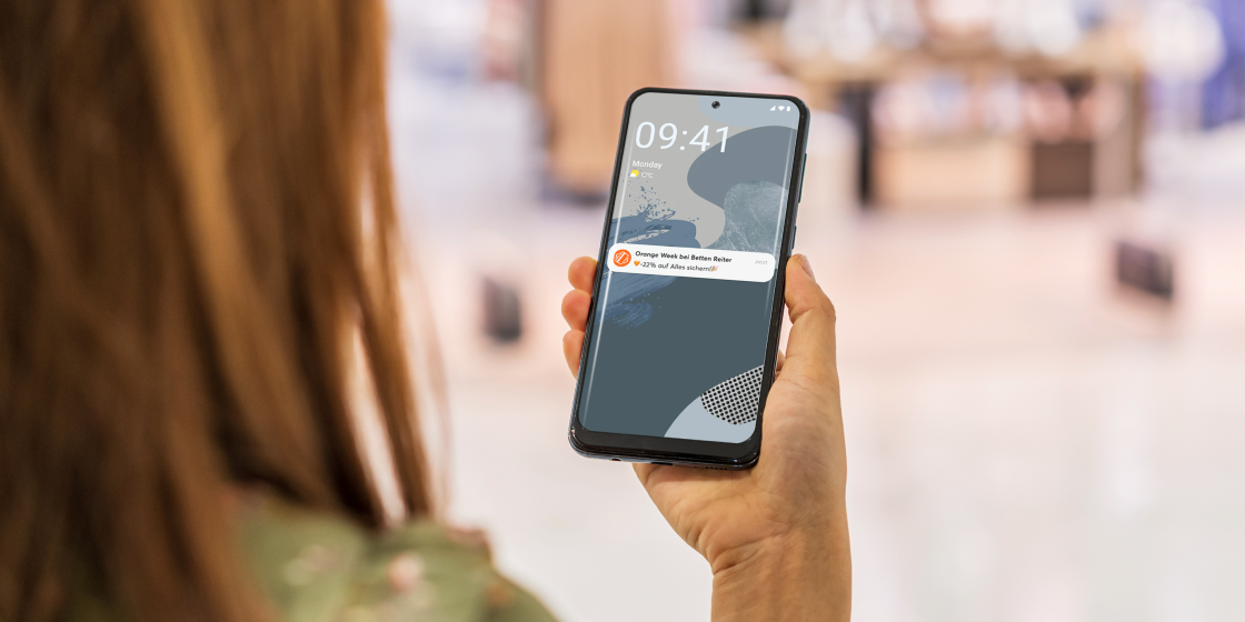 A smartphone held by a woman, showing a mobile-pocket ad push notification on the lock screen.