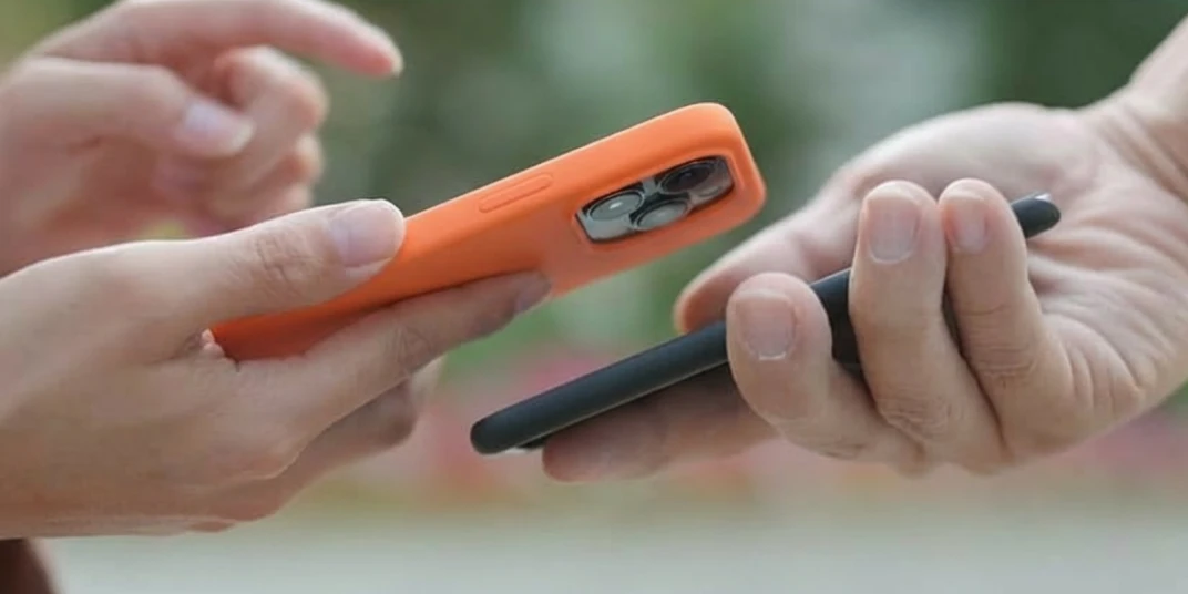 Di due persone si vedono solo le mani con i loro smartphone: un riferimento simbolico alla funzione “Condividi carte” nell'app per le carte fedeltà mobile-pocket