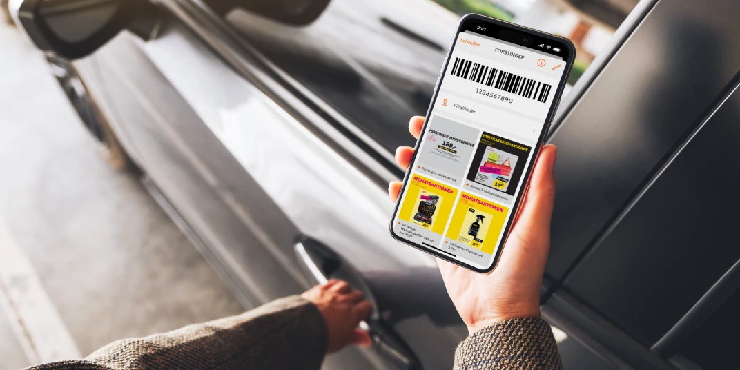 Mann beim Einsteigen in das Auto mit Smartphone in der Hand auf dem am Screen die mobile-pocket Kundenkartenapp zu sehen ist mit den Angeboten und Kartendetails von Forstinger.